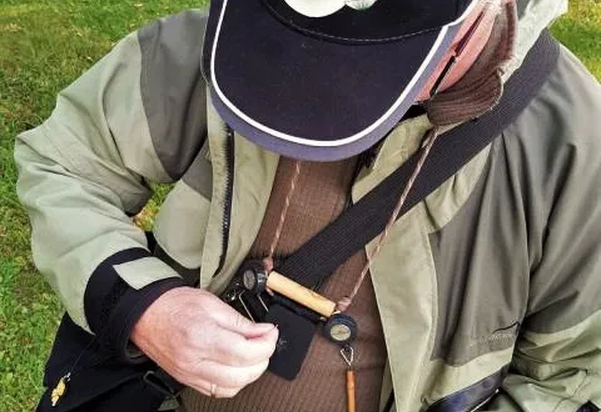 Ein Angler in Outdoor-Kleidung hält eine Dose mit künstlichen Fliegenködern in der Hand.
