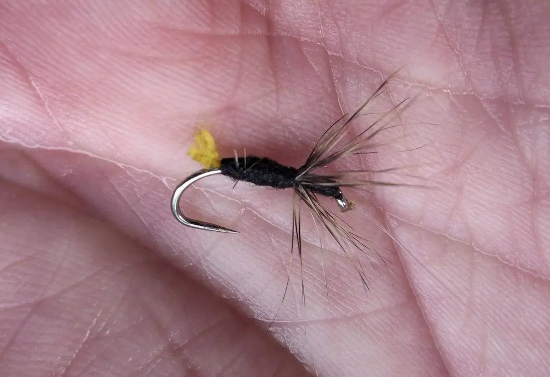 Eine künstliche Fliegenangel liegt auf einer offenen Handfläche.